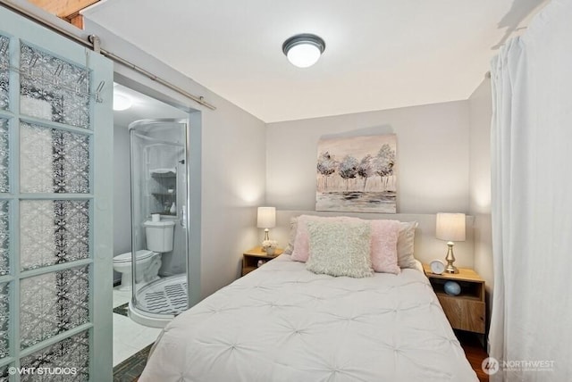 bedroom featuring a barn door and ensuite bath