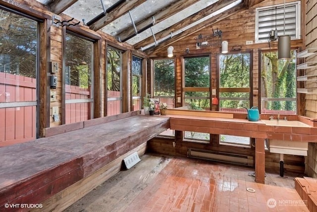 sunroom with vaulted ceiling with beams, wood walls, and a baseboard heating unit