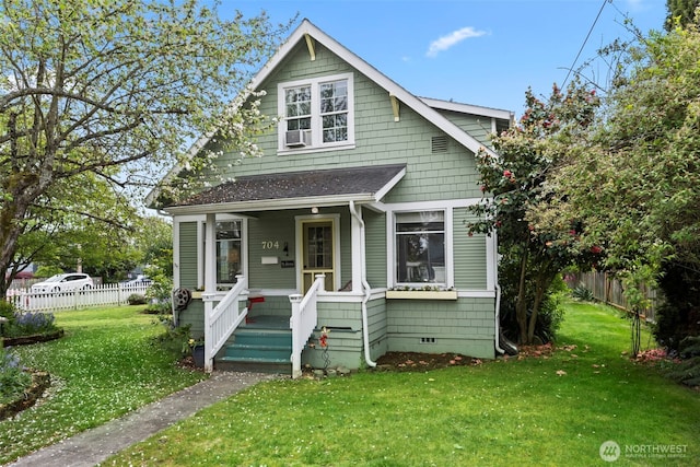 bungalow-style house featuring a shingled roof, fence, covered porch, and a front yard