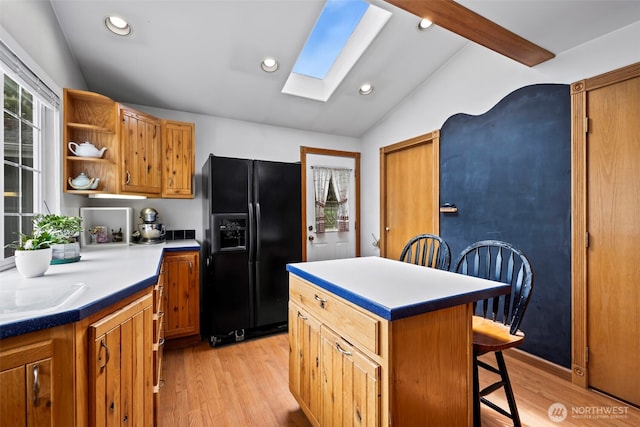 kitchen featuring open shelves, black refrigerator with ice dispenser, lofted ceiling with skylight, a kitchen bar, and light wood-type flooring
