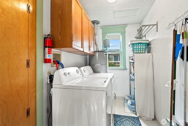 laundry room featuring washing machine and dryer, light tile patterned flooring, attic access, gas water heater, and cabinet space