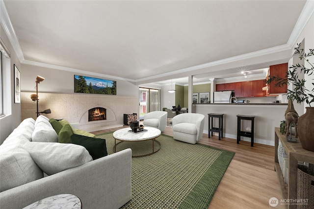 living room with ornamental molding, light wood-style flooring, and a brick fireplace