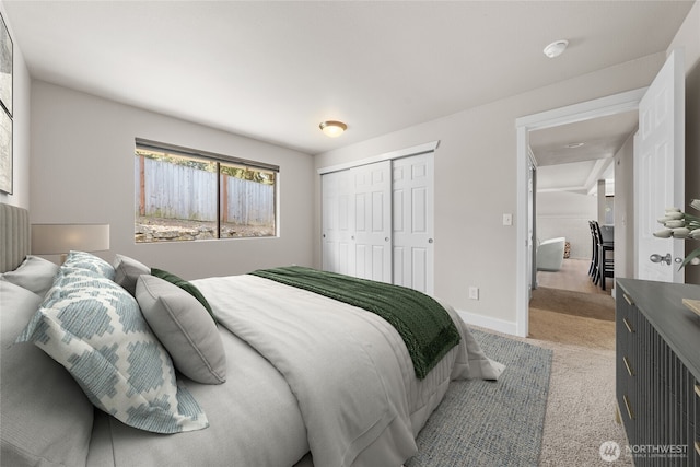 bedroom with a closet, baseboards, and light carpet