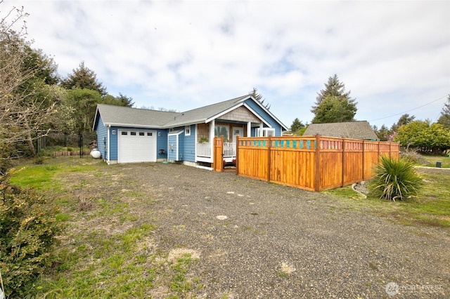 ranch-style house featuring an attached garage, fence, and gravel driveway