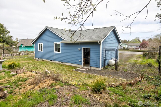 rear view of house featuring a lawn, fence, roof with shingles, and a detached garage