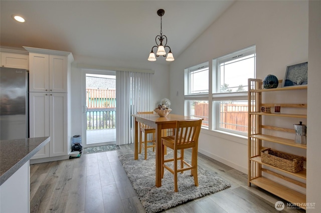 dining space with recessed lighting, vaulted ceiling, an inviting chandelier, and light wood finished floors