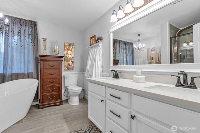 bathroom with an inviting chandelier, a sink, a shower stall, and double vanity