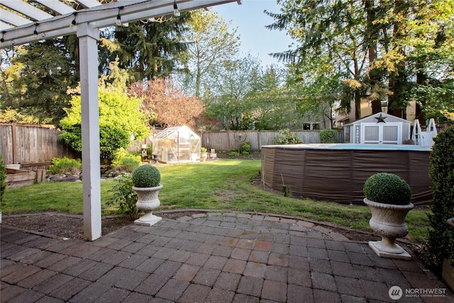 view of patio / terrace featuring a pergola, an exterior structure, an outdoor structure, a fenced backyard, and a swimming pool