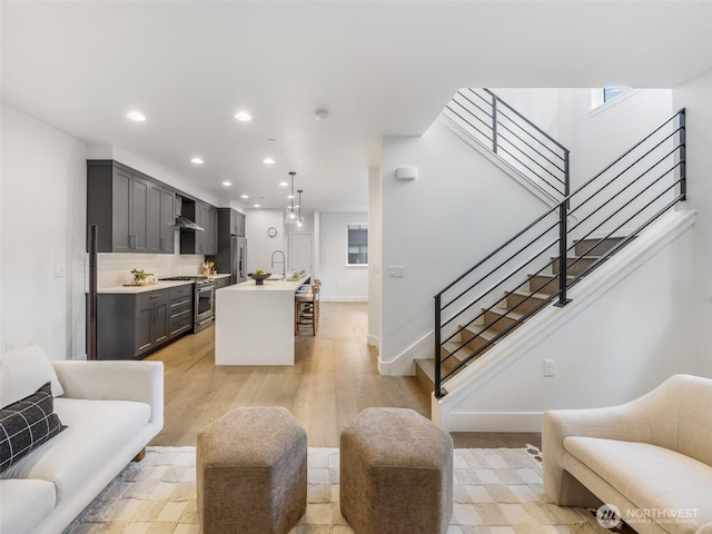 living room featuring light wood-style flooring, stairs, recessed lighting, and baseboards