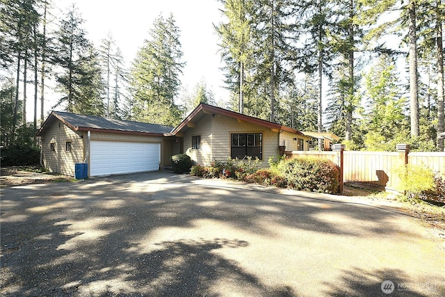 view of front of home with fence, a garage, and aphalt driveway