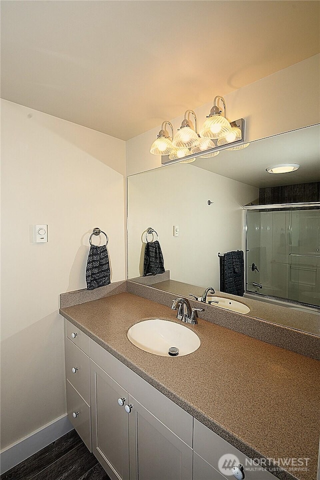 full bathroom with baseboards, wood finished floors, a shower with door, and vanity