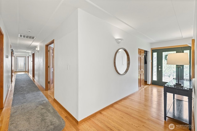 corridor with light wood-style floors, baseboards, and visible vents