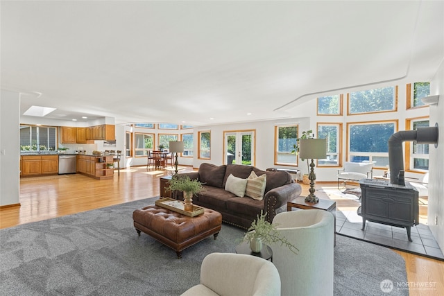 living area featuring recessed lighting, a wood stove, light wood finished floors, and a skylight