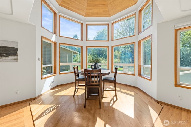 dining room with baseboards, light wood-type flooring, and a towering ceiling