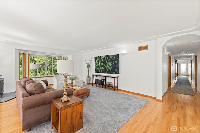living room with visible vents, arched walkways, and light wood finished floors