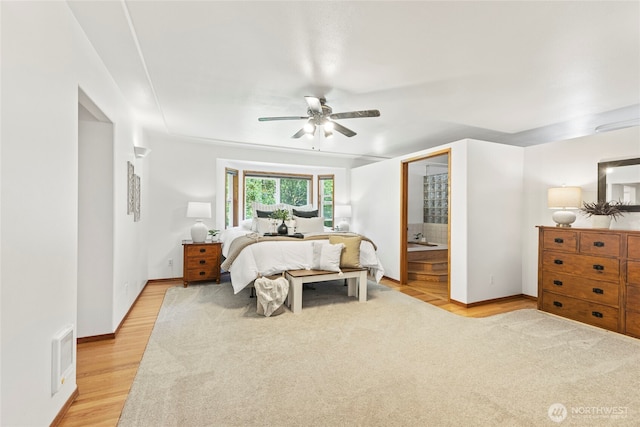 bedroom featuring visible vents, baseboards, ensuite bathroom, ceiling fan, and light wood finished floors