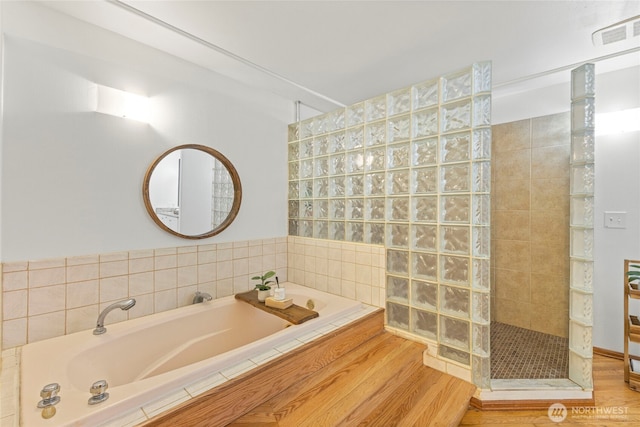 bathroom with wood finished floors, walk in shower, a garden tub, and visible vents