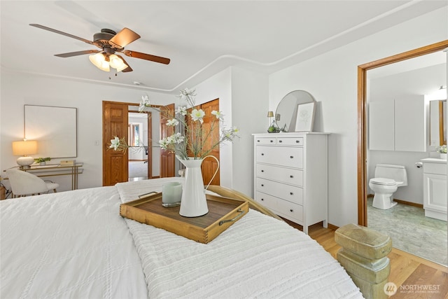 bedroom with ensuite bathroom, a ceiling fan, and light wood finished floors