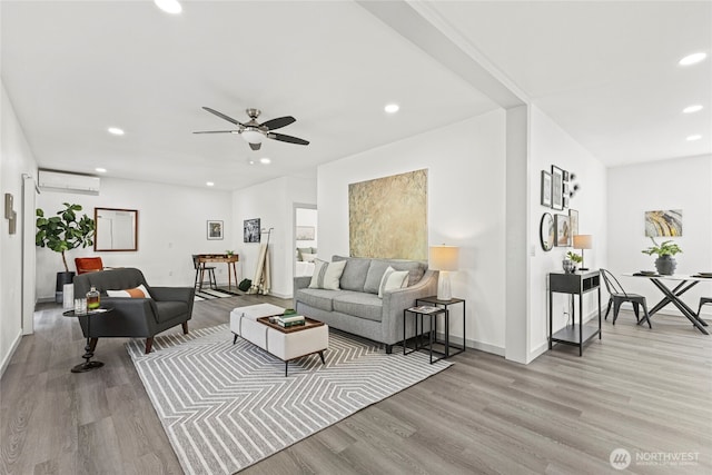 living room with an AC wall unit, recessed lighting, baseboards, and wood finished floors