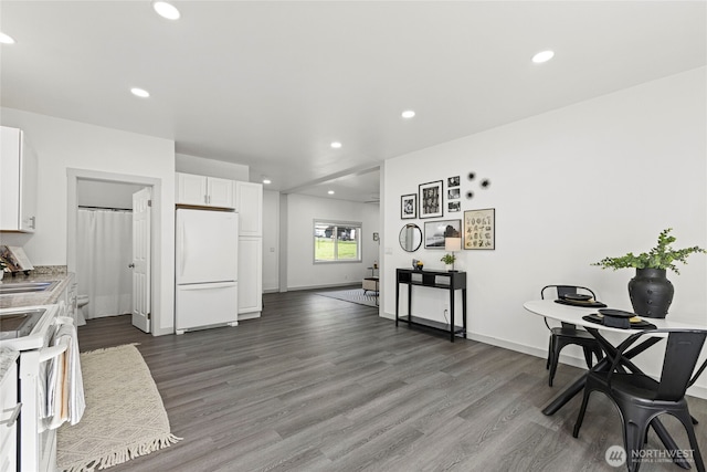 kitchen with white cabinetry, light countertops, recessed lighting, white appliances, and dark wood-type flooring