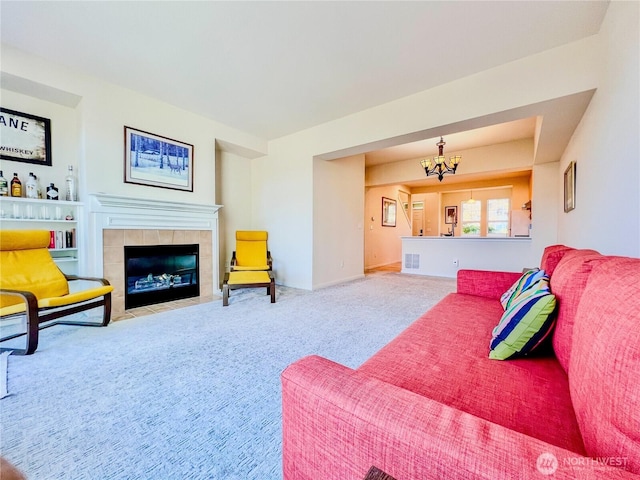 living area featuring visible vents, carpet flooring, a tile fireplace, and a notable chandelier