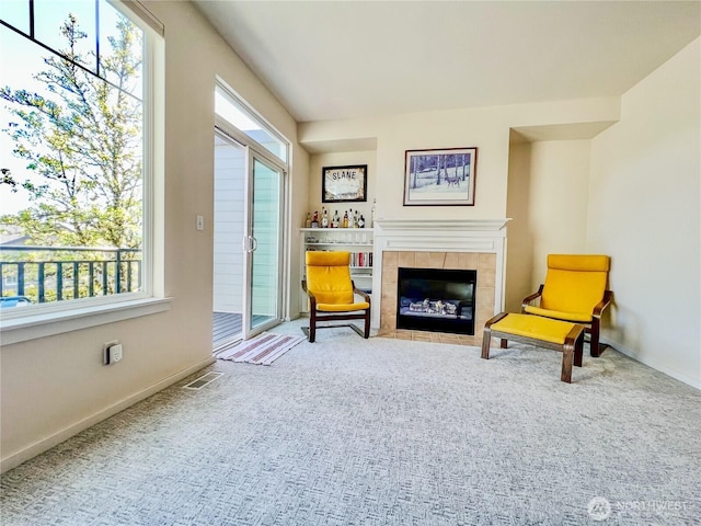 sitting room with a tiled fireplace, baseboards, carpet flooring, and visible vents