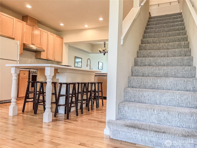 stairway featuring wood-type flooring, recessed lighting, and a notable chandelier