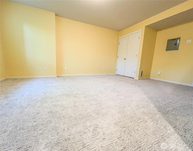 unfurnished room featuring baseboards, electric panel, and light carpet
