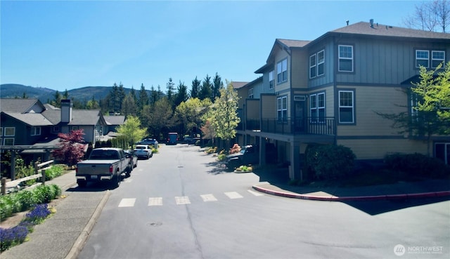 view of road featuring a residential view, a mountain view, sidewalks, and curbs