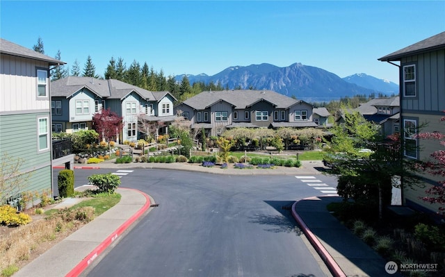 view of road with a mountain view, a residential view, sidewalks, and curbs
