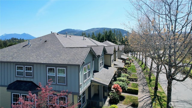 view of side of property with board and batten siding, a mountain view, and roof with shingles