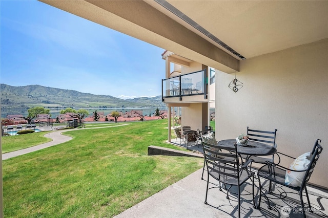 view of yard featuring a mountain view, outdoor dining area, a balcony, and a patio area