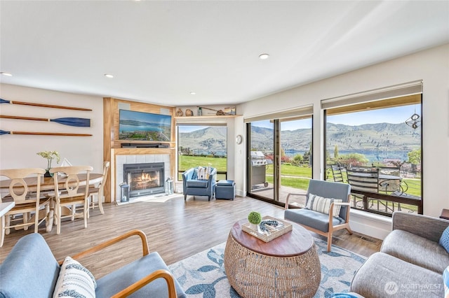 living room with a tiled fireplace, recessed lighting, and wood finished floors
