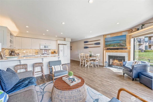 living area with recessed lighting, a tile fireplace, wood finished floors, and baseboards