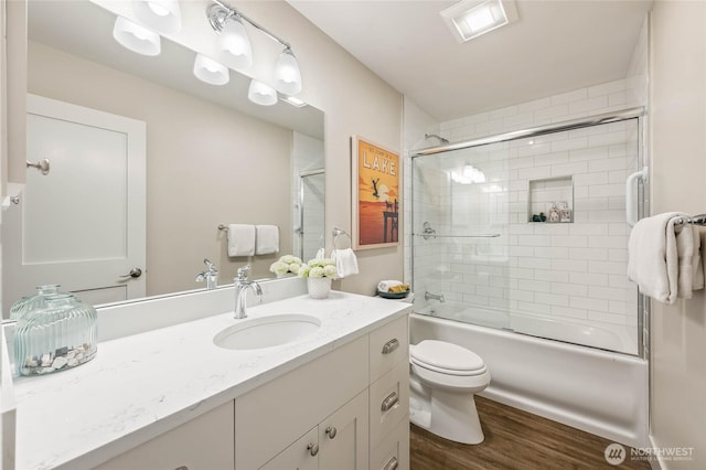 full bathroom featuring wood finished floors, toilet, enclosed tub / shower combo, and vanity