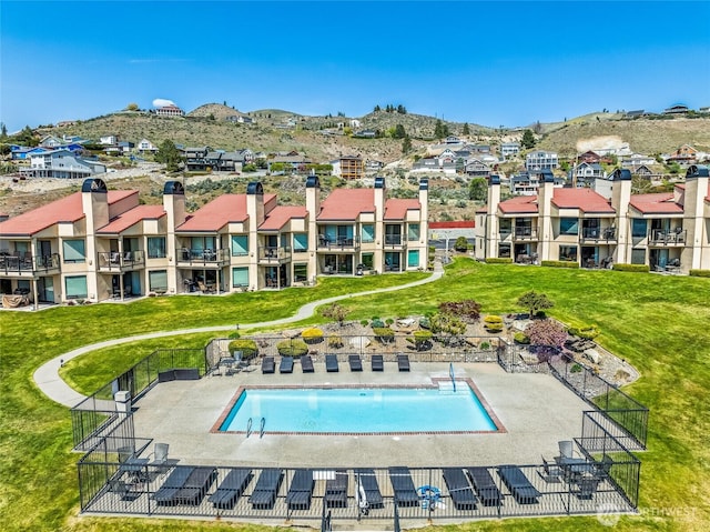 community pool with a residential view, a lawn, and fence
