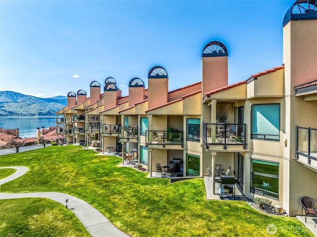 view of property's community with a water and mountain view and a lawn
