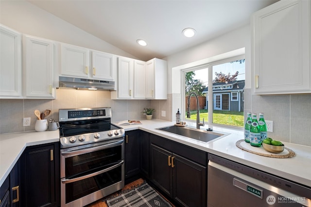 kitchen with white cabinets, appliances with stainless steel finishes, a sink, lofted ceiling, and under cabinet range hood