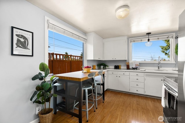 6357 37th Ave SW, Seattle, WA 98126 - kitchen featuring wall oven, light wood-type flooring, white cabinetry, a sink, and light countertops