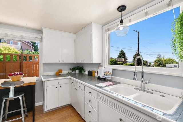 6357 37th Ave SW, Seattle, WA 98126 - kitchen with a sink, light countertops, light wood-type flooring, and white cabinets
