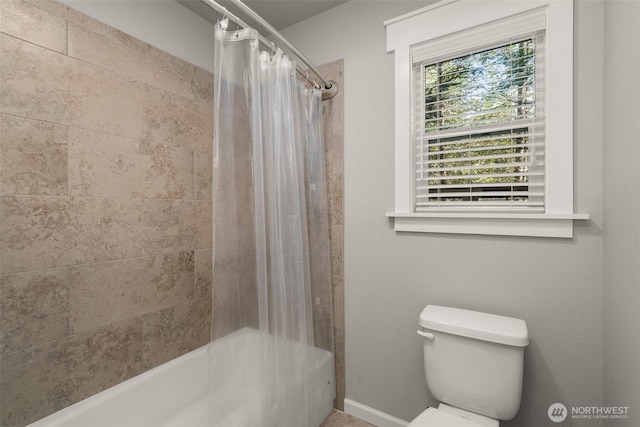 bathroom with baseboards, shower / bath combo with shower curtain, and toilet