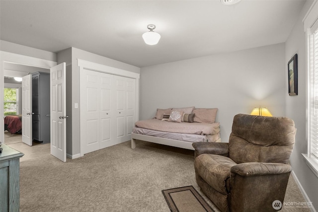 bedroom with light colored carpet, baseboards, and a closet