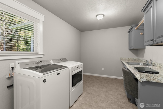 clothes washing area with cabinet space, washing machine and clothes dryer, light carpet, a sink, and baseboards