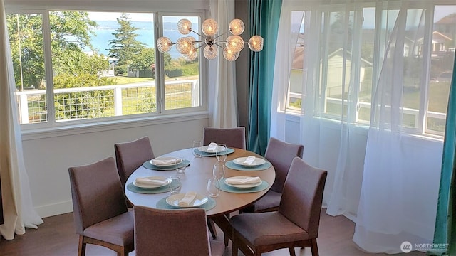 dining room with an inviting chandelier, baseboards, plenty of natural light, and wood finished floors