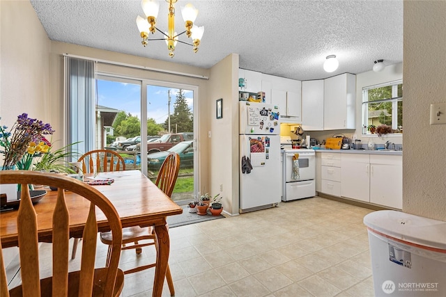 kitchen with white appliances, white cabinetry, a textured ceiling, and a chandelier