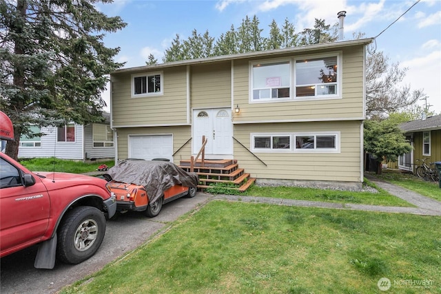 raised ranch featuring an attached garage, driveway, and a front lawn