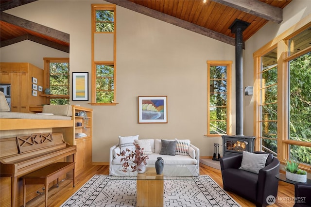 living room with wood ceiling, plenty of natural light, a wood stove, and beam ceiling
