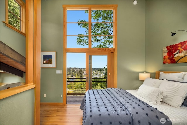 bedroom with access to exterior, wood finished floors, and multiple windows
