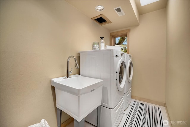 laundry room with laundry area, visible vents, washing machine and dryer, a sink, and baseboards
