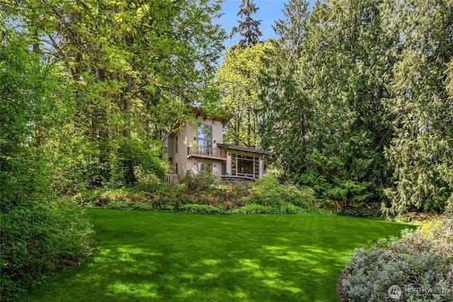view of yard with a view of trees and a balcony